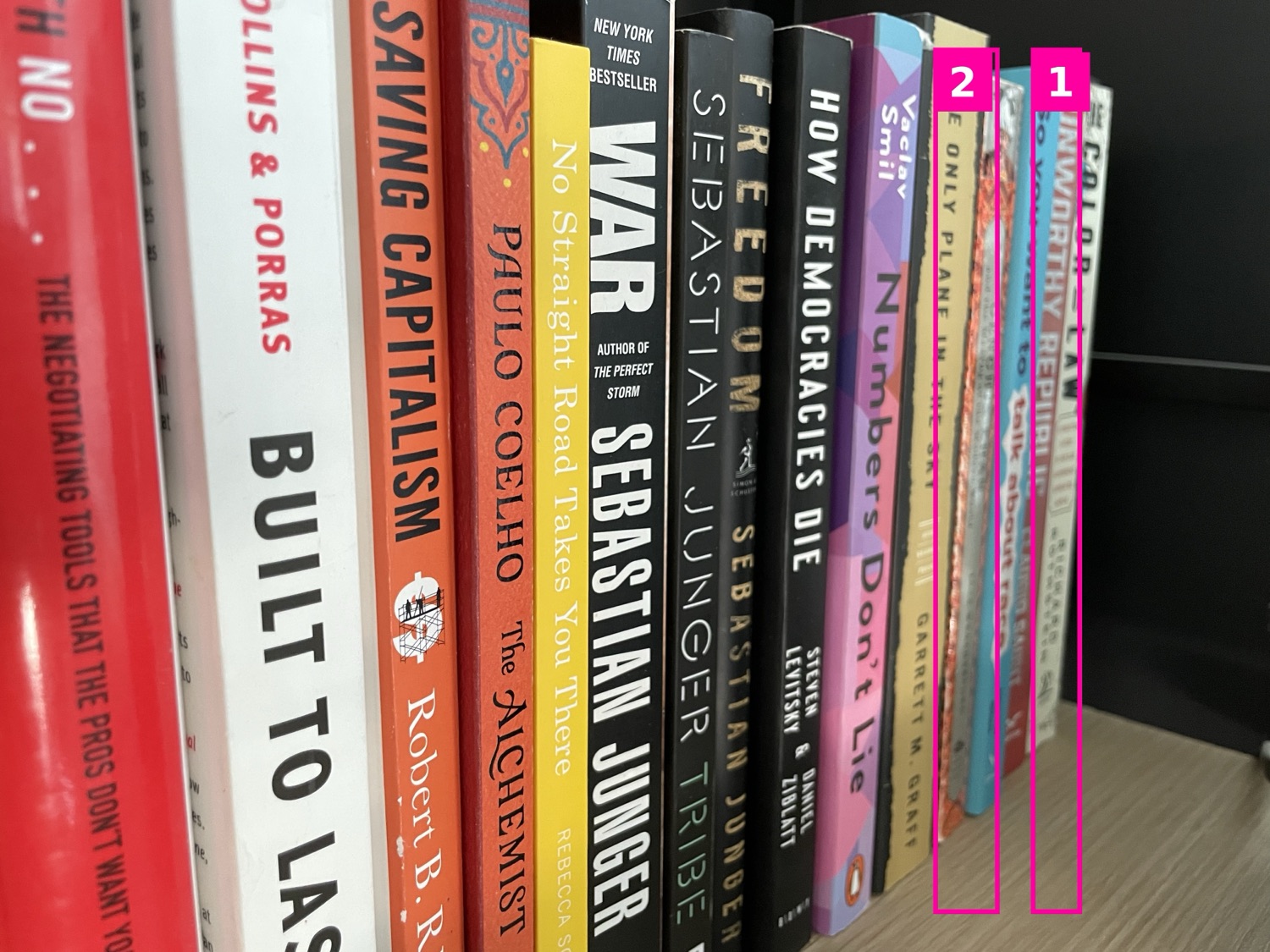 A bookshelf photo with magenta numbered boxes drawn around two hard-to-read book spines for verification